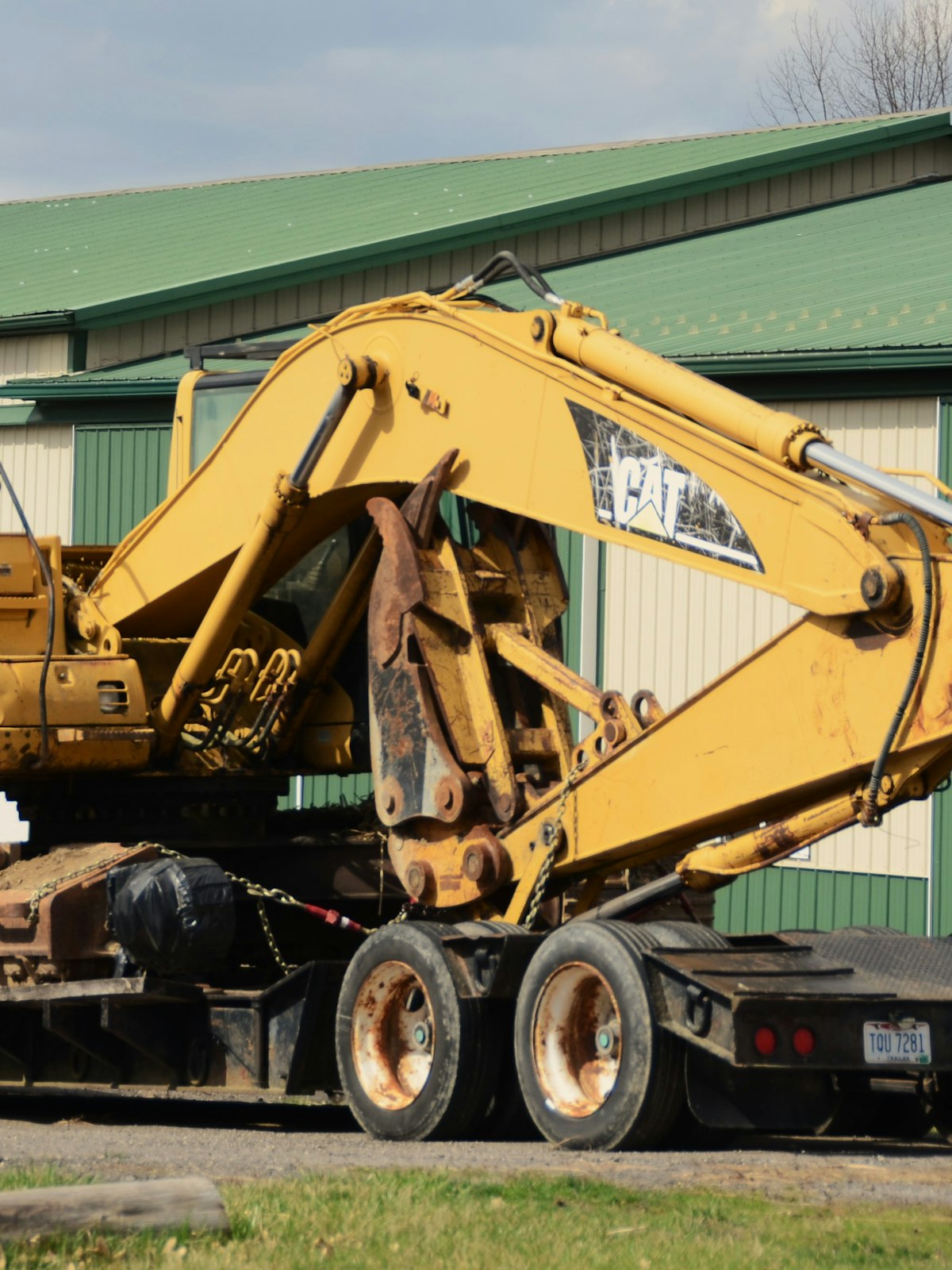 A yellow excavator strapped to a flatbed trailer